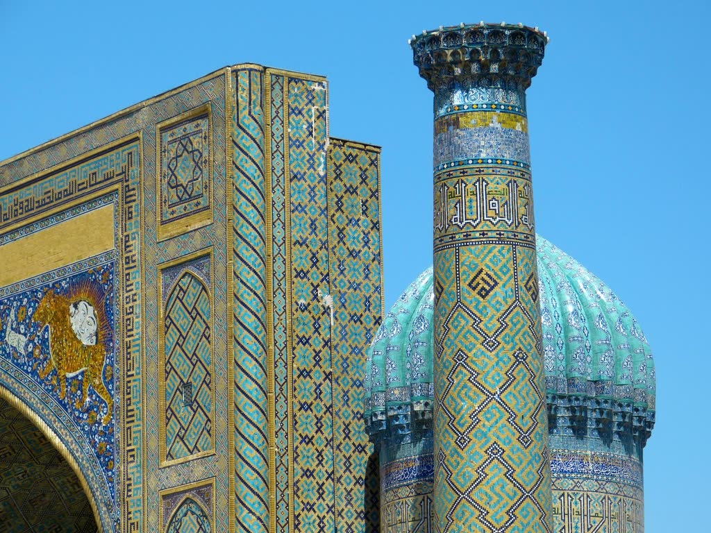 The Registan in Samarkand: tiled madrasa facades and a minaret against a clear blue sky