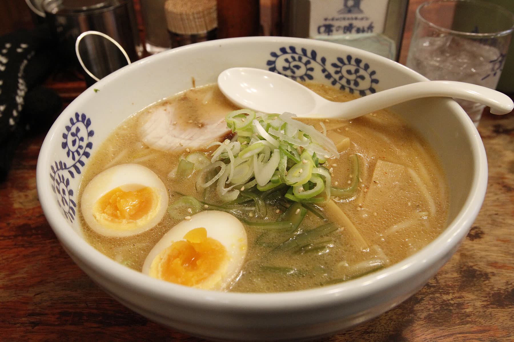 A bowl of miso ramen with soft-boiled egg and spring onion at a counter in Sapporo